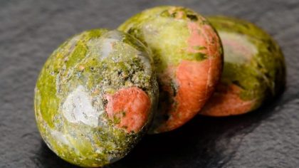 Three unakite round cabochons on black stone plate.