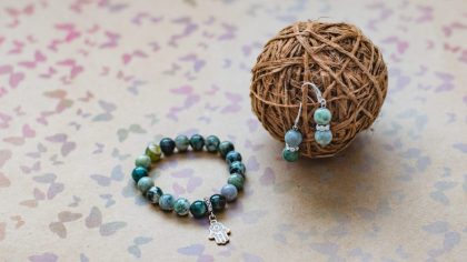 Close-up of a necklace and earrings of green jasper and silver on a background with multi-colored butterflies.
